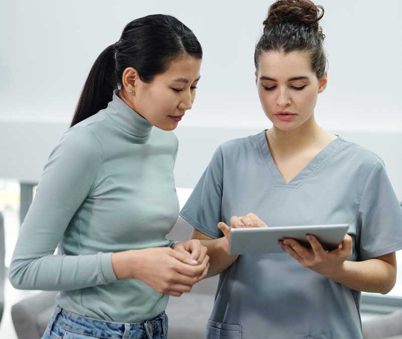 nurse discussing test results with female patient tablet