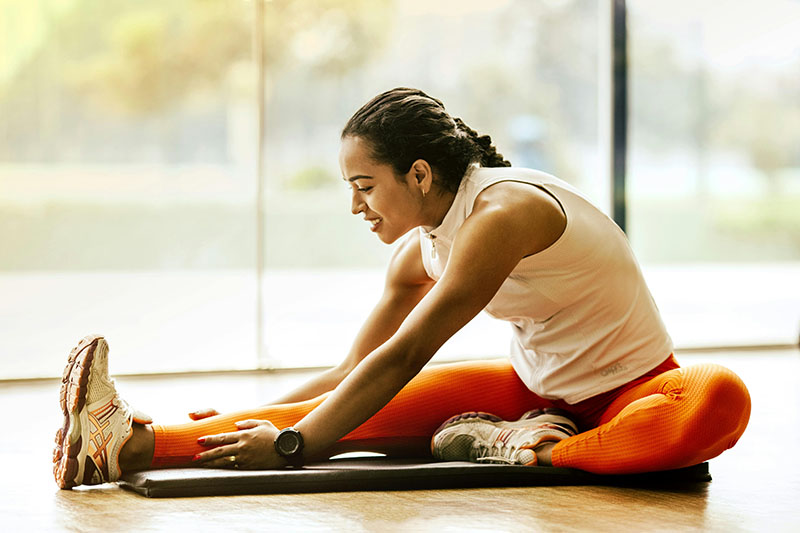 latina woman in orange tights stretching after workout